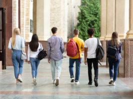 Group of students walking in college campus after classes, back view