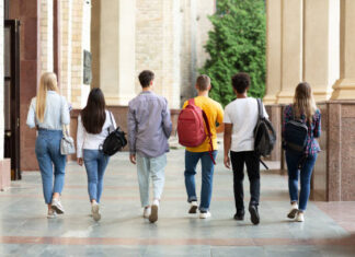 Group of students walking in college campus after classes, back view