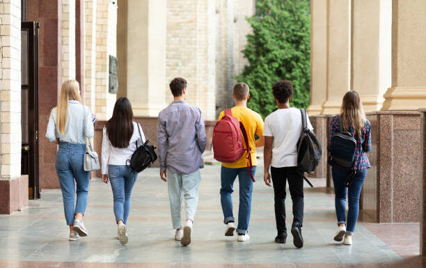 Group of students walking in college campus after classes, back view