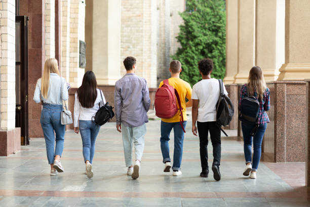 Group of students walking in college campus after classes, back view
